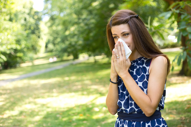 young woman blowing her nose in the park